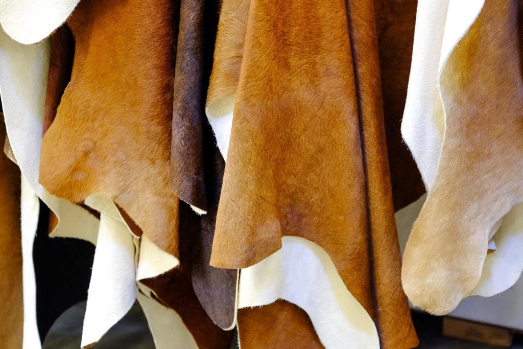 Hanging pieces of tanned cowhide leather ready to be turned into luxury fashion.