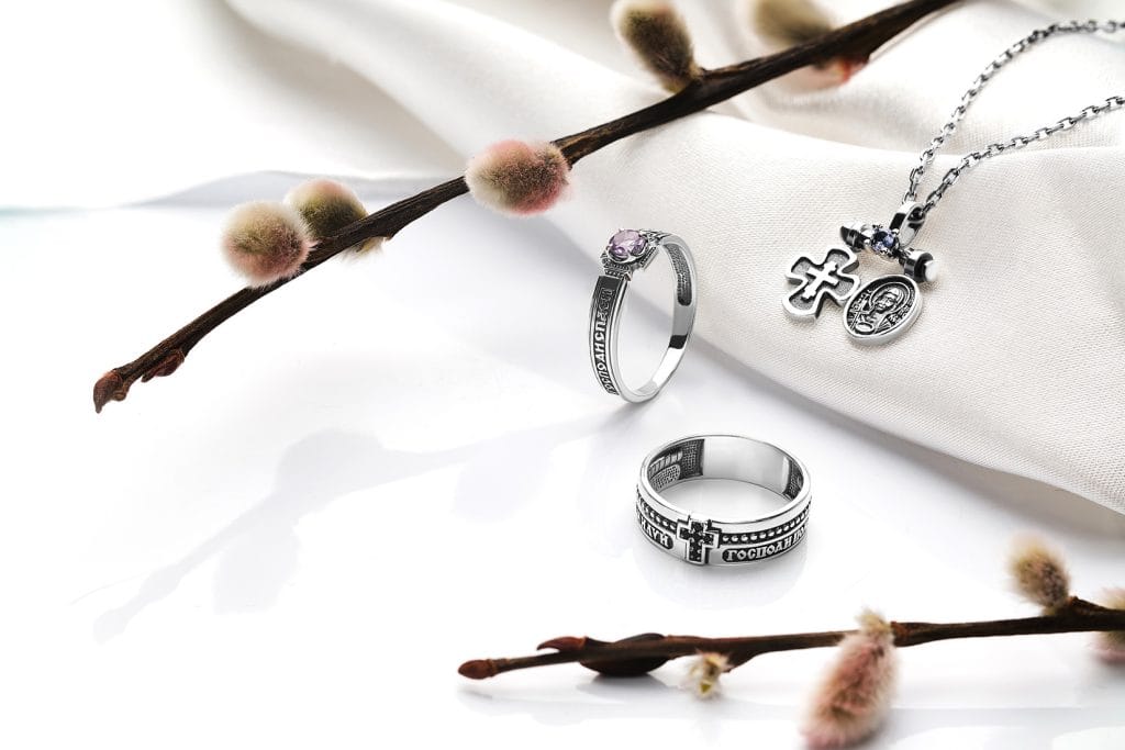 A display of silver and gold rosary rings, each featuring intricate designs and perfect for both spiritual and stylish wear.