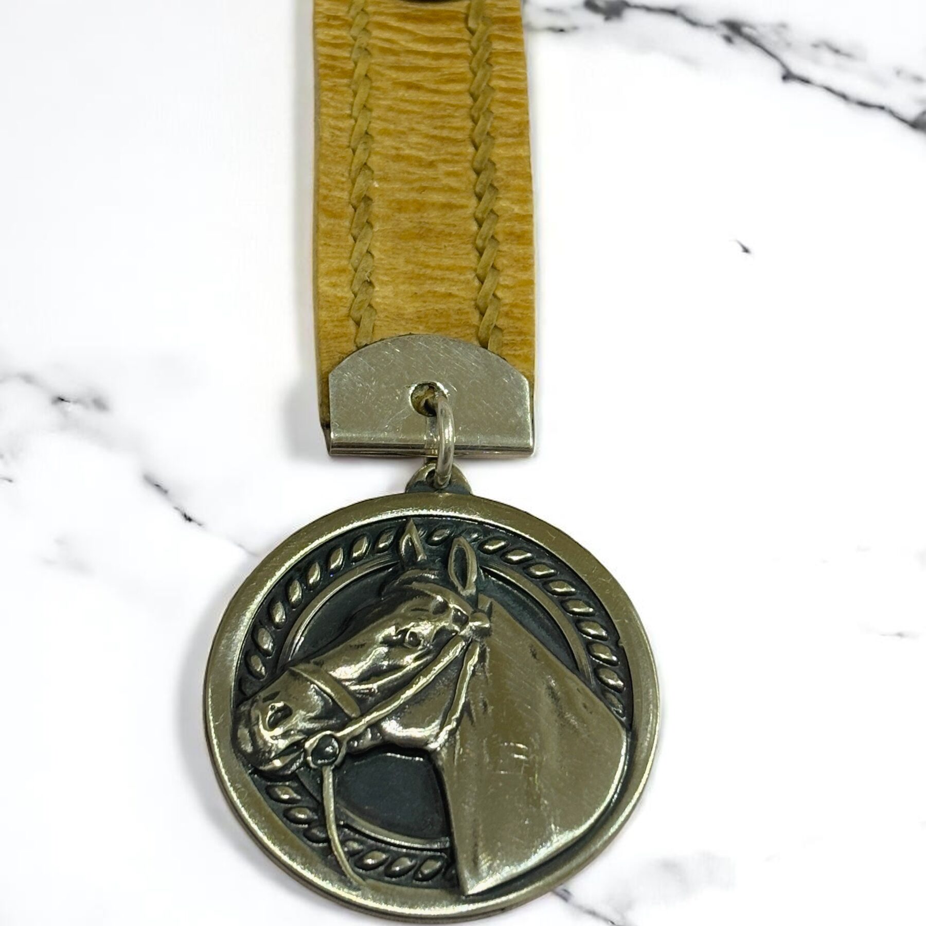 Sterling silver horse pendant on black background to highlight engraving and shine