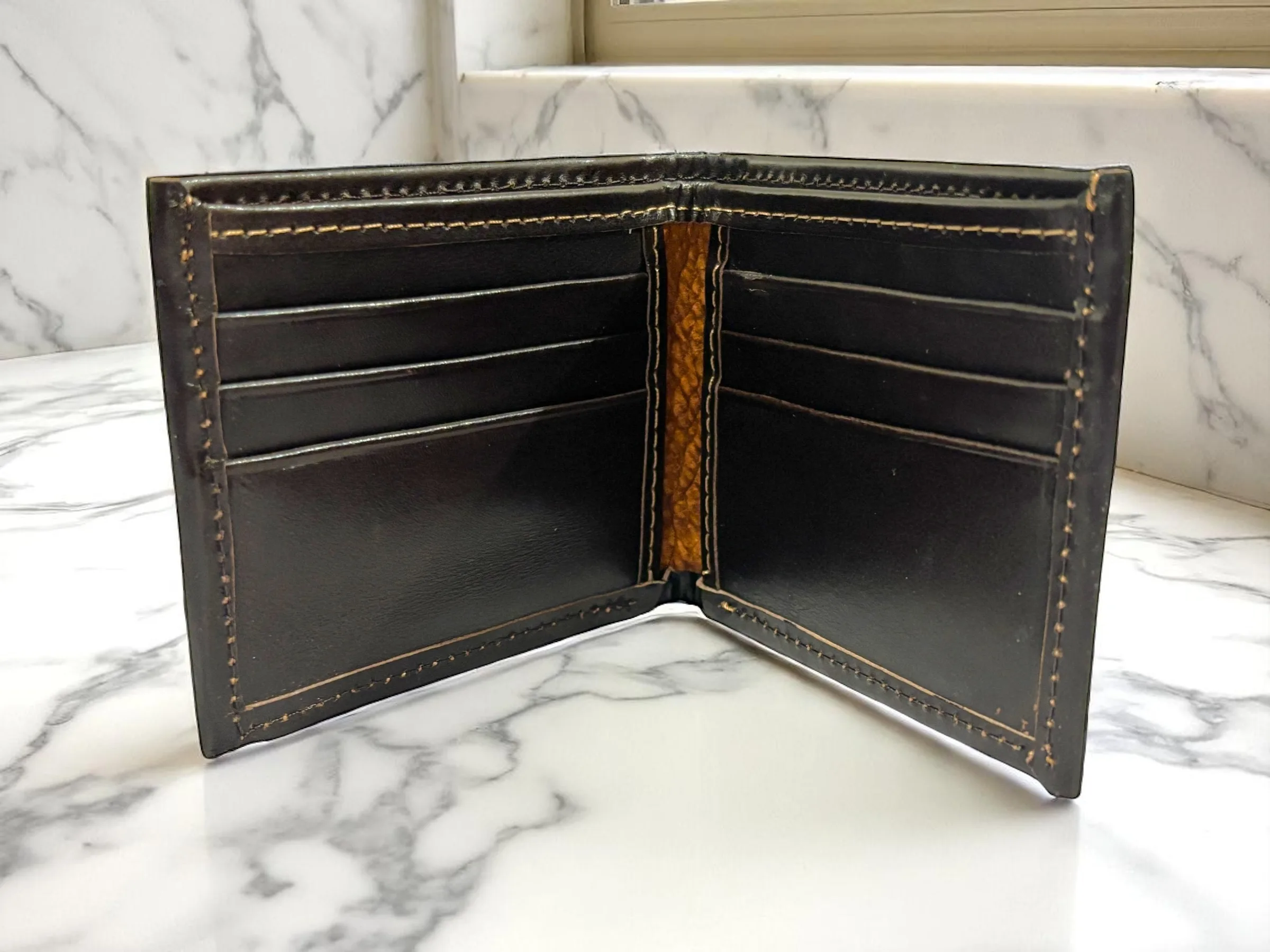 Open carpincho bifold wallet displaying card slots and full leather interior.