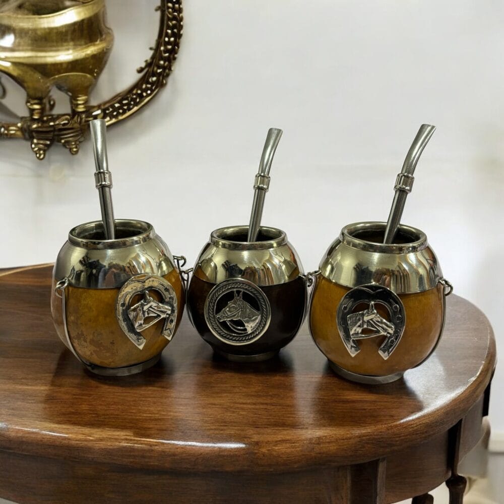 Three handcrafted gaucho-style mate cups with horse medallions and Omega-shaped horseshoe emblems.