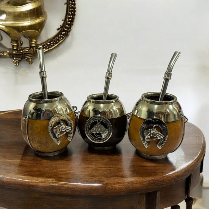 Three handcrafted gaucho-style mate cups with horse medallions and Omega-shaped horseshoe emblems.