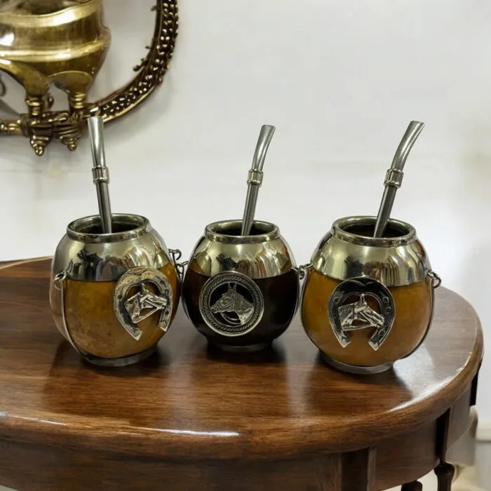 Three handcrafted gaucho-style mate cups with horse medallions and Omega-shaped horseshoe emblems.