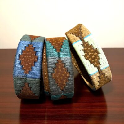 Group of three Carpincho embroidered belts with colorful threads and brown leather details, showcasing Argentine craftsmanship