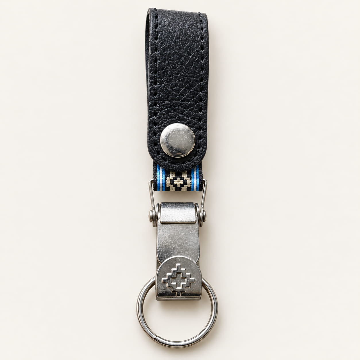 lack leather belt clip keychain with geometric Guarda Pampa metal motif and woven band edged in sky blue and white.