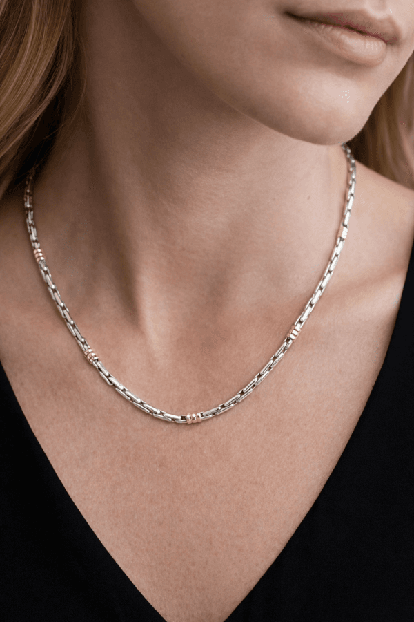 Close-up of a model wearing a handmade sterling silver rice link chain with subtle 18kt gold accents