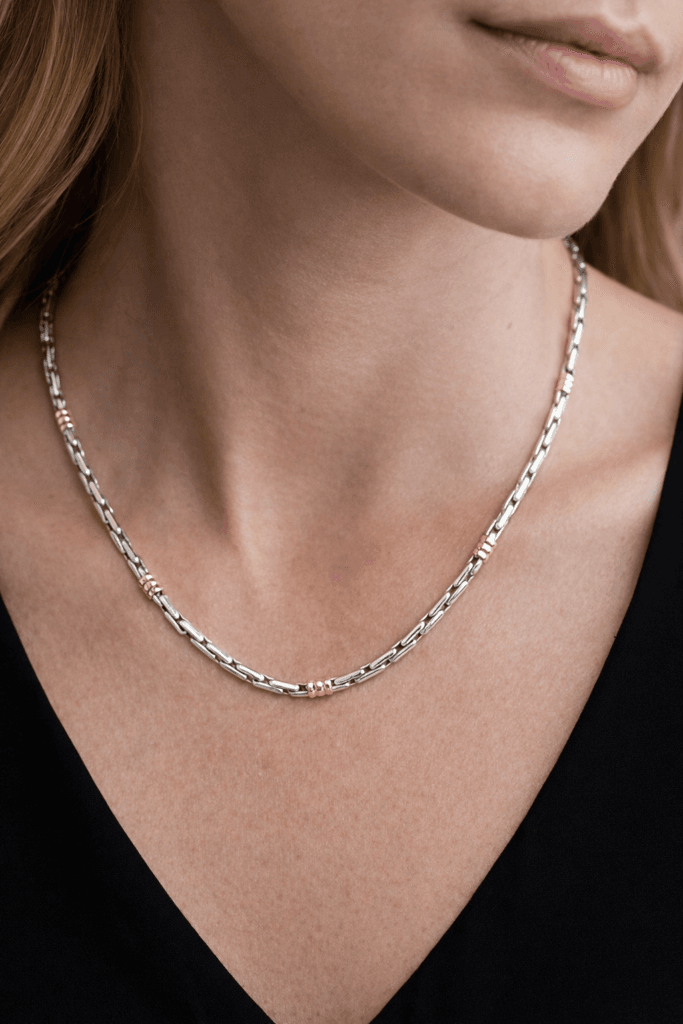 Close-up of a model wearing a handmade sterling silver rice link chain with subtle 18kt gold accents