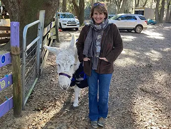 A lady posing next to a donkey