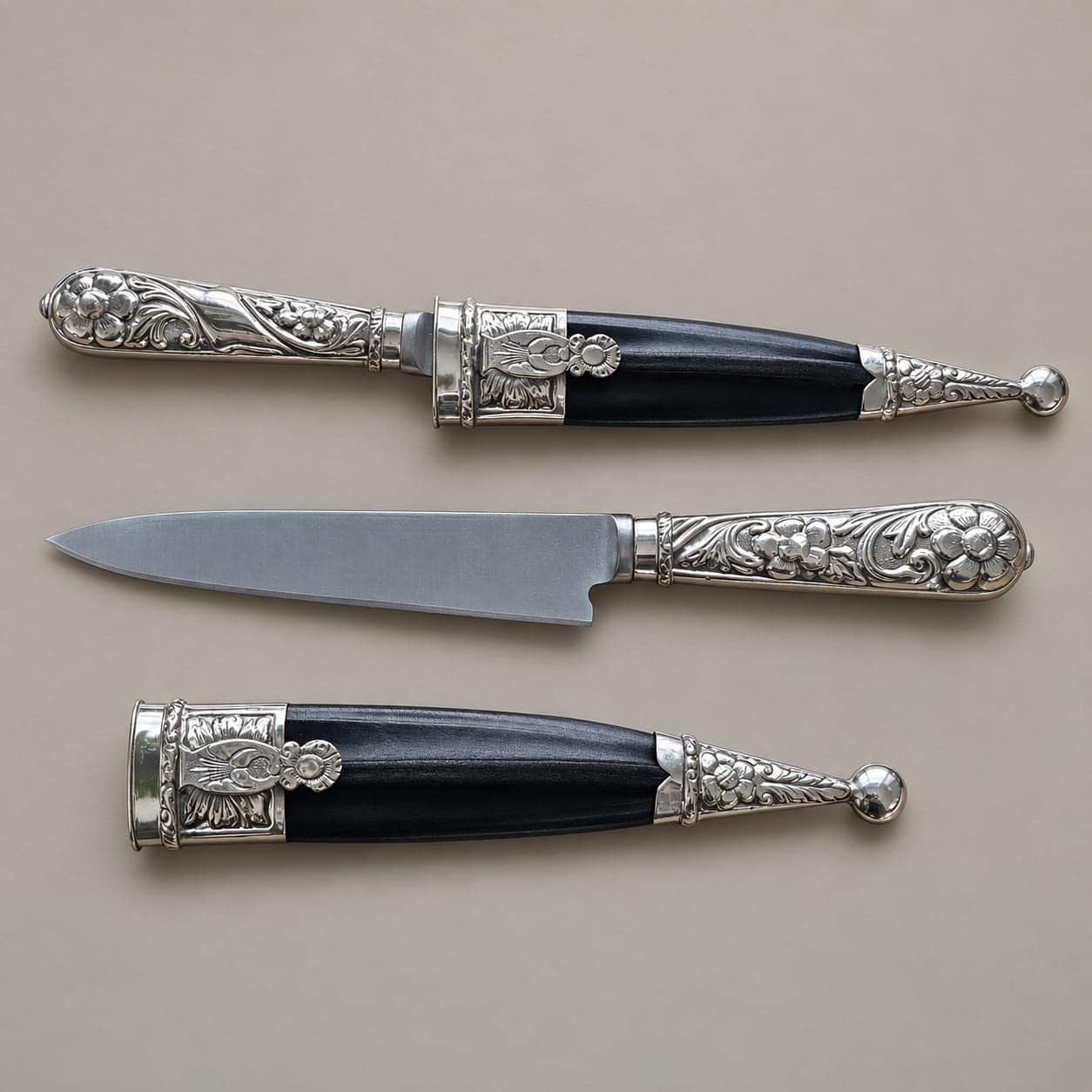 Argentine gaucho knife shown sheathed and unsheathed, with a floral engraved alpaca handle and black sheath