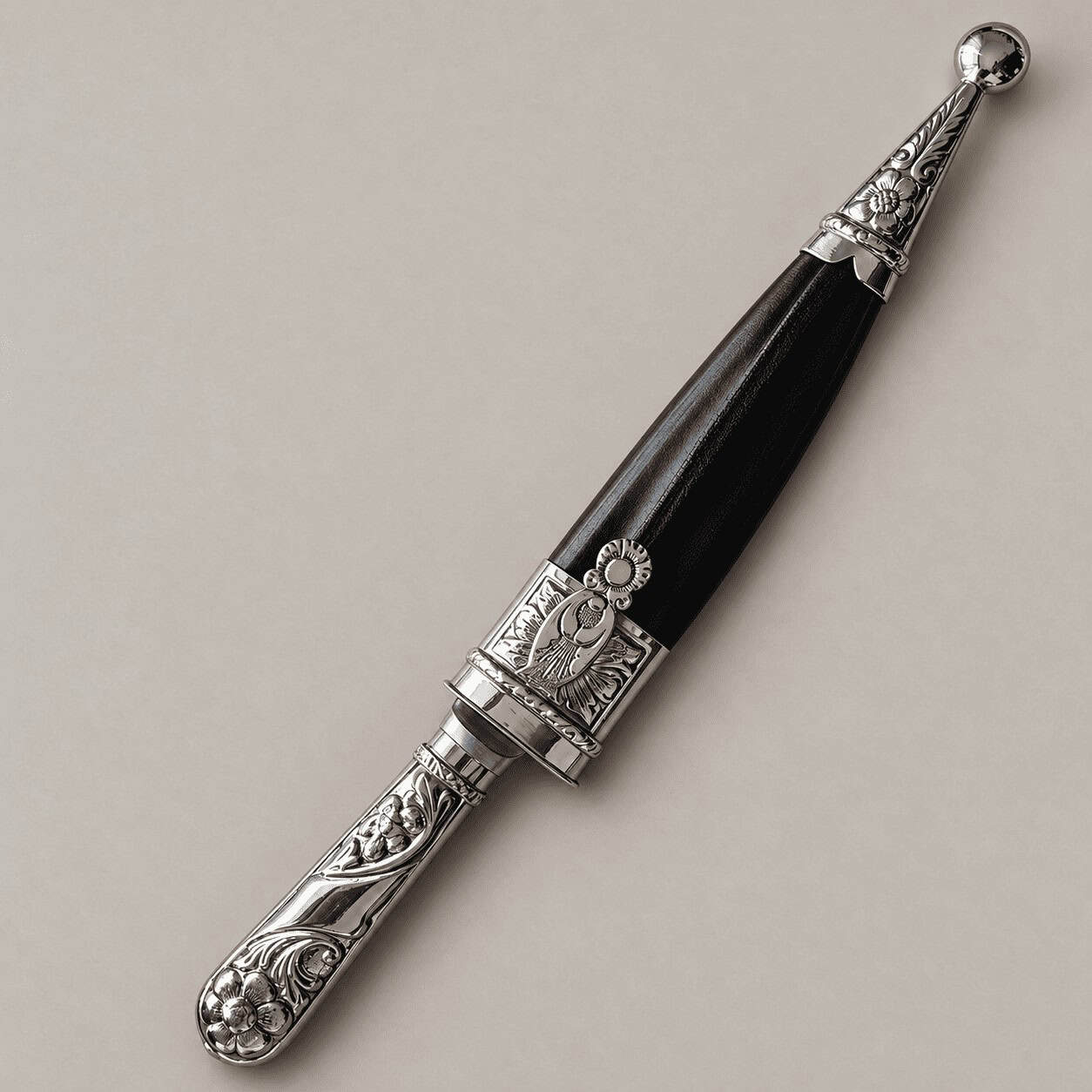 Sheathed Argentine knife with black leather, an engraved alpaca handle and silver-toned fittings.