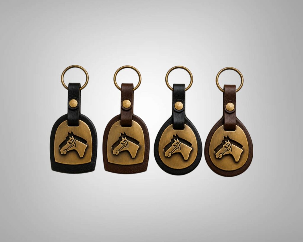 Four handmade Argentine leather horse head keychains featuring dome and round silhouettes in black and dark brown leather with brass horse motifs.