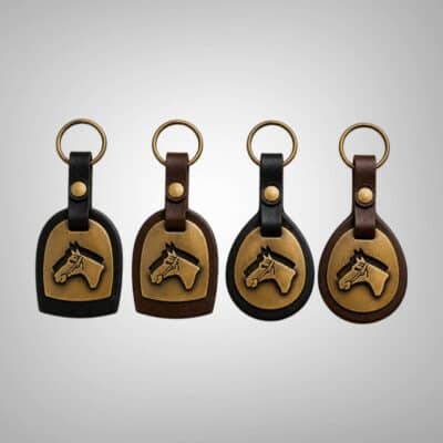 Four handmade Argentine leather horse head keychains featuring dome and round silhouettes in black and dark brown leather with brass horse motifs.