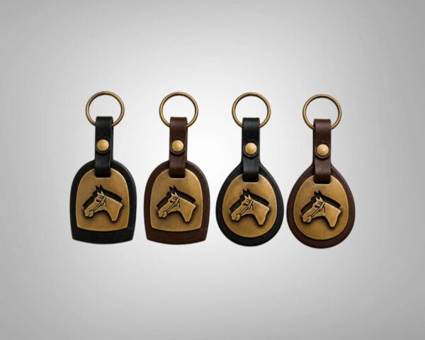 Four handmade Argentine leather horse head keychains featuring dome and round silhouettes in black and dark brown leather with brass horse motifs.