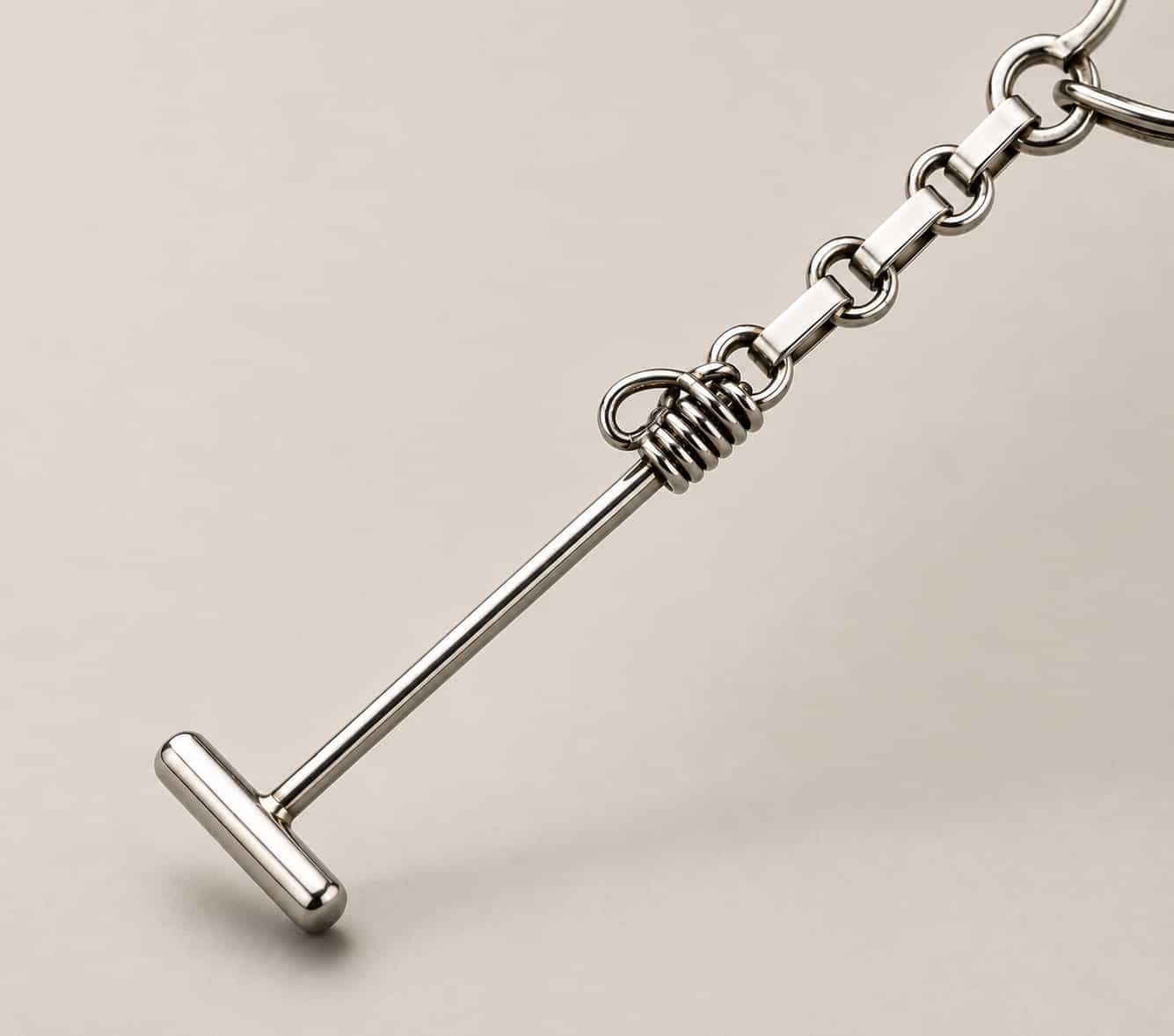 Close-up of a handmade Argentine polo mallet keychain crafted from solid alpaca silver, showing the polished mallet head and wrapped detail