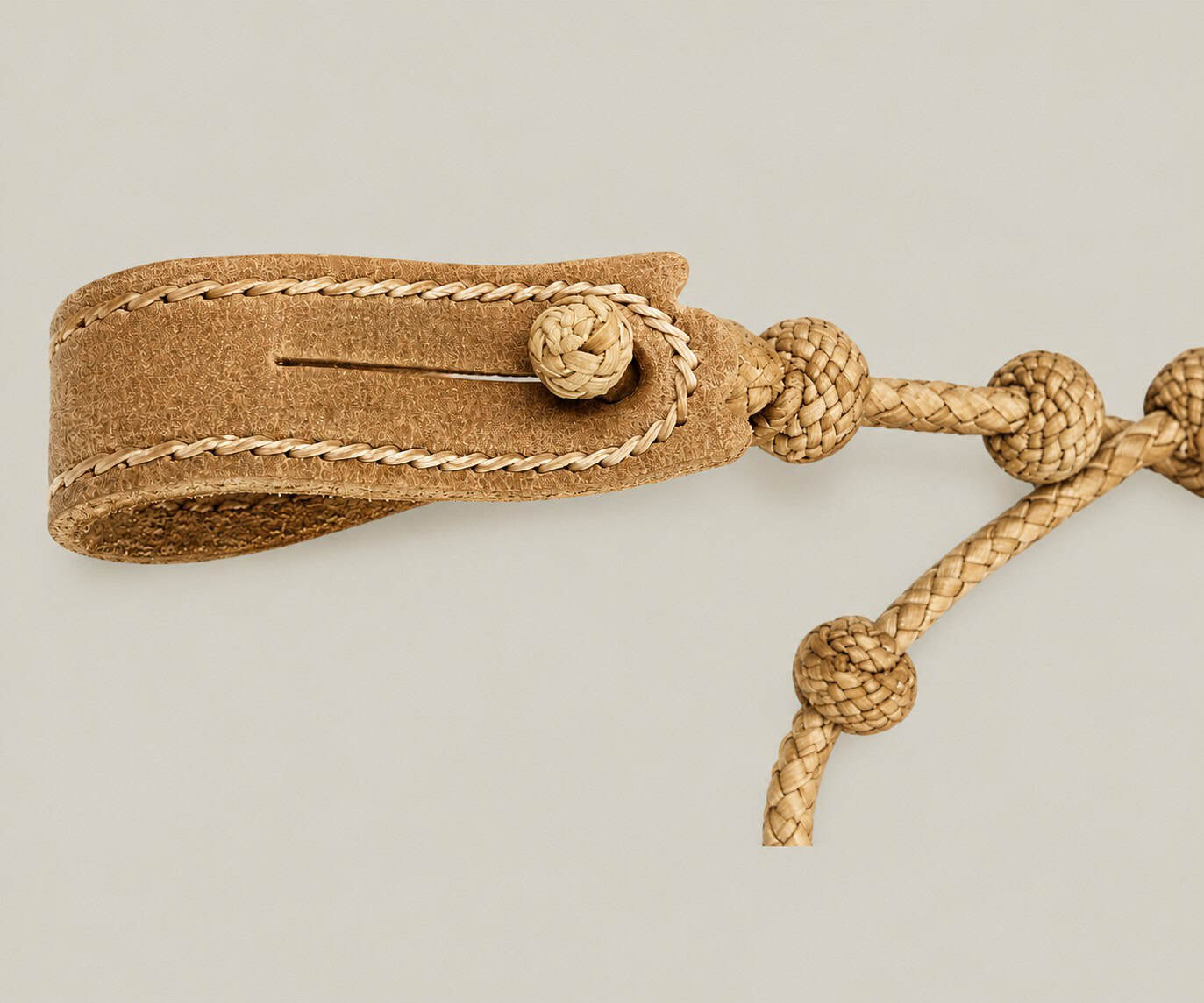 Close-up of a handmade Argentine rawhide cattle counter keychain showing the traditional presilla closure and hand-braided gaucho knots.