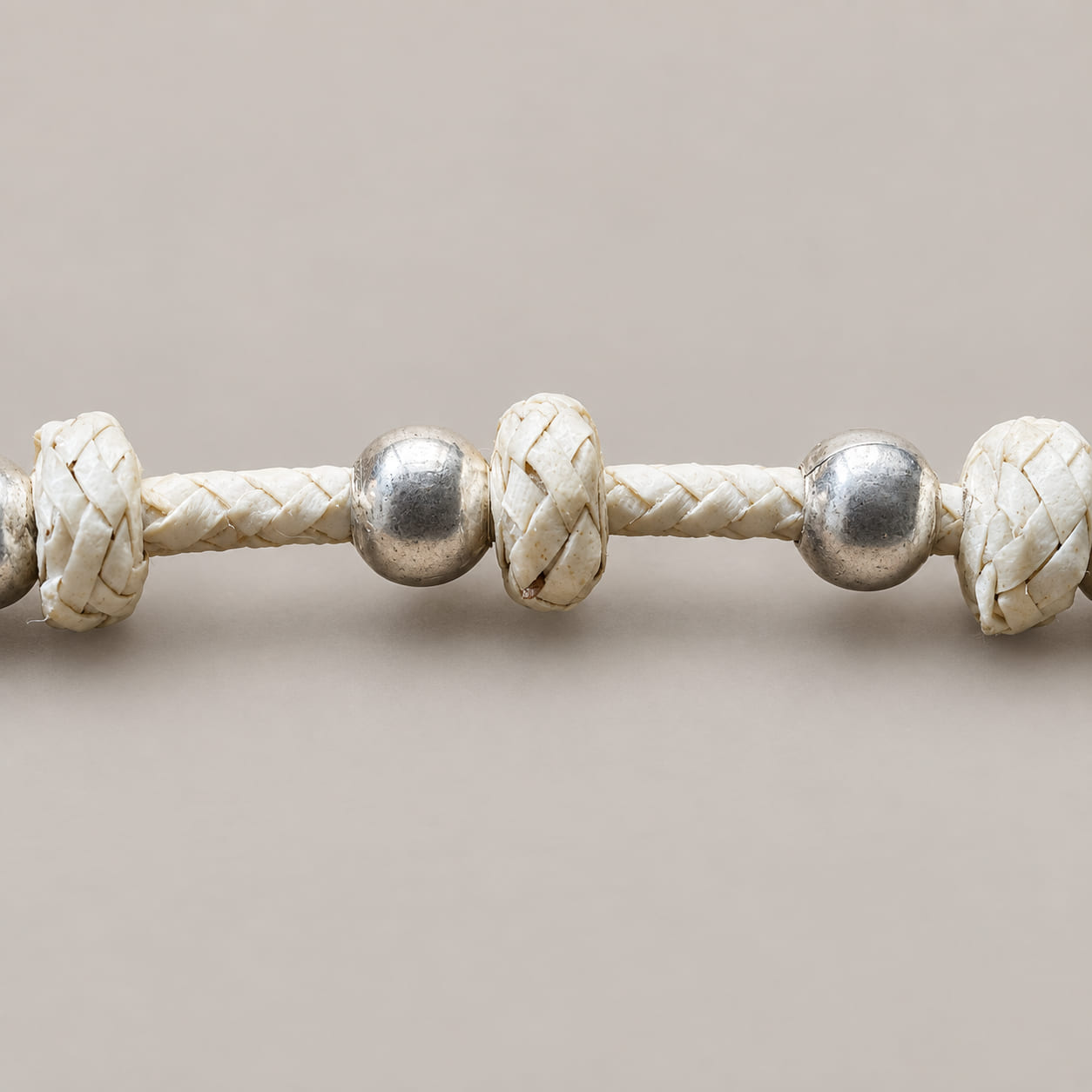 Close-up of silver-tone beads and braided rawhide spacers on an Argentine horse halter