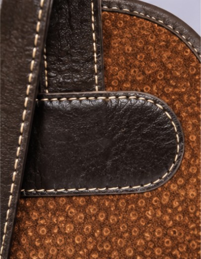 Close-up of handcrafted leather trim and reinforced stitching on a genuine capybara leather backpack.