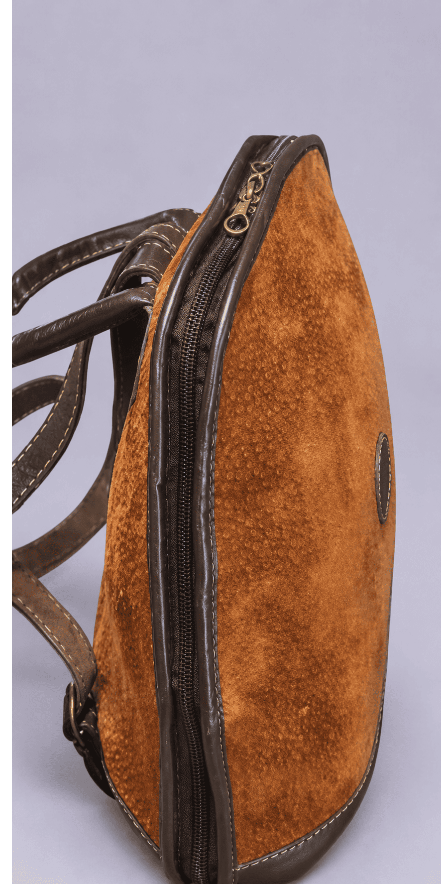 Side view of a handmade capybara leather backpack featuring a full-opening zip closure and premium Argentine cowhide leather trim.