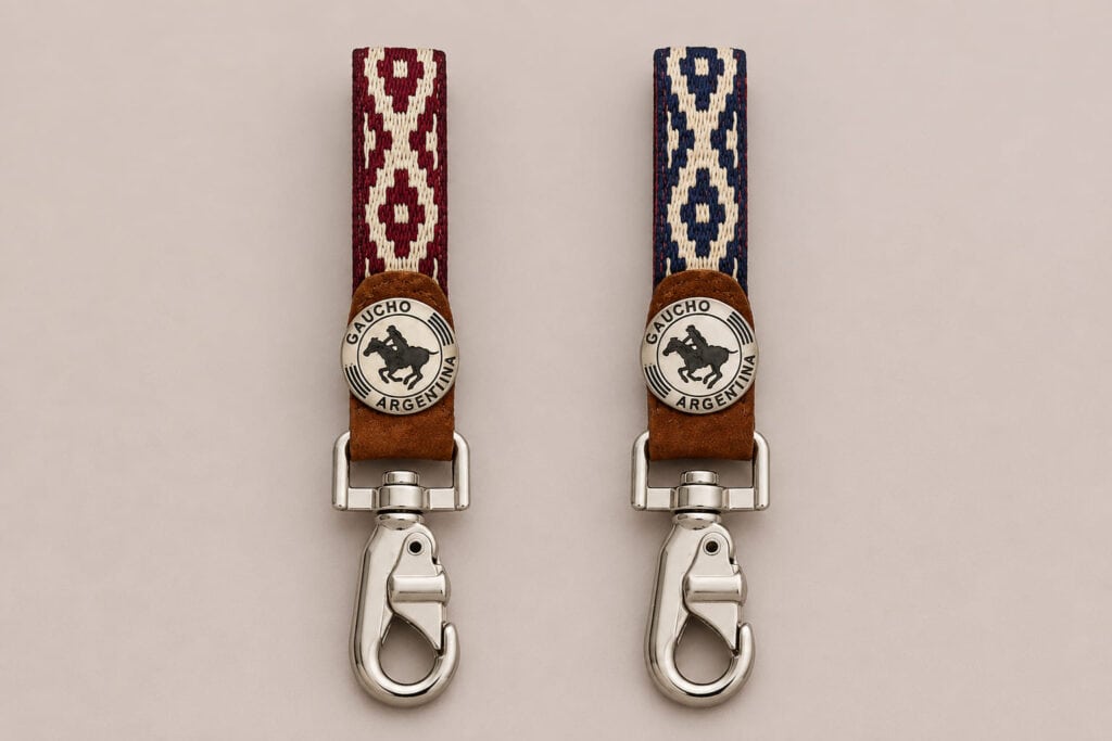 Two handcrafted Argentine polo key rings displayed side by side, one with a red Guarda Pampa weave and the other with a blue pattern. Both feature genuine capybara leather, a Gaucho Argentina polo medallion and polished swivel clips.