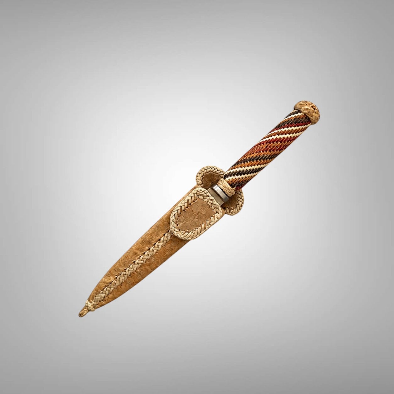 Sheathed Argentine gaucho knife set diagonally against a soft gray background, with an intricate hand-braided rawhide handle in tan, rust, charcoal and ivory.