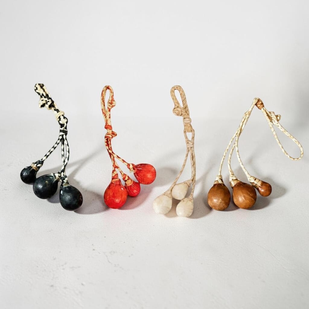 Handmade rawhide mini boleadoras keyrings in four color variations, artisan crafted in Argentina.