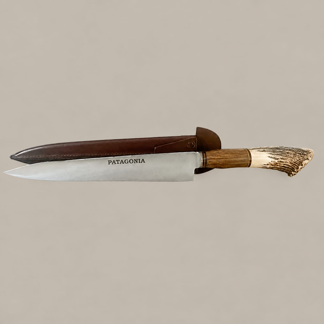 Horizontal view of a PATAGONIA-marked gaucho knife with a curved staghorn and hardwood handle and brown leather sheath behind it.