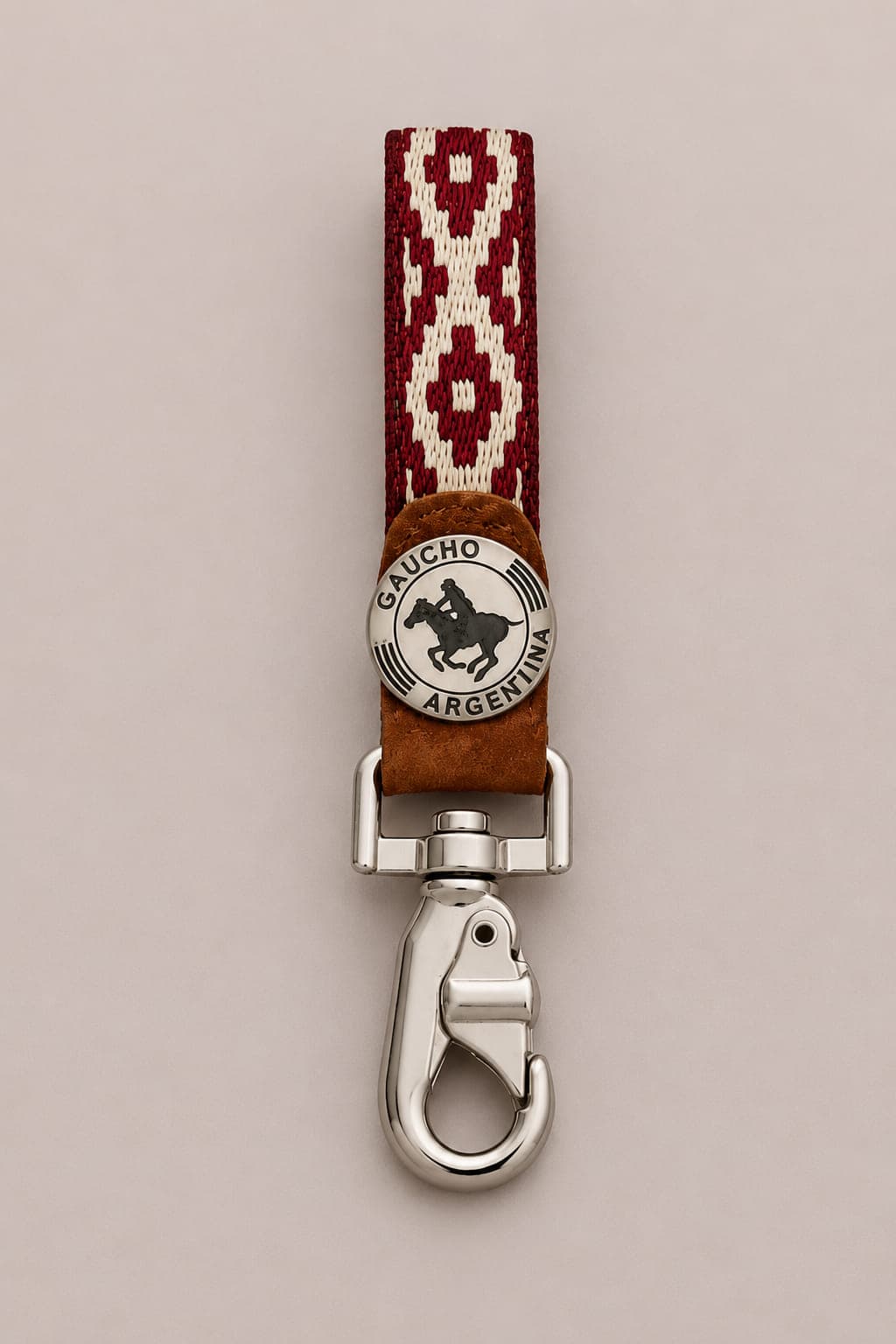 Handcrafted Argentine polo key ring featuring a red woven Guarda Pampa strap, genuine capybara leather, a Gaucho Argentina polo medallion and a polished silver-tone swivel clip.