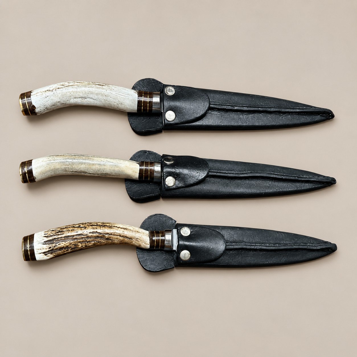 Three handmade Argentine gaucho steak knives with natural staghorn handles and fitted black leather sheaths.