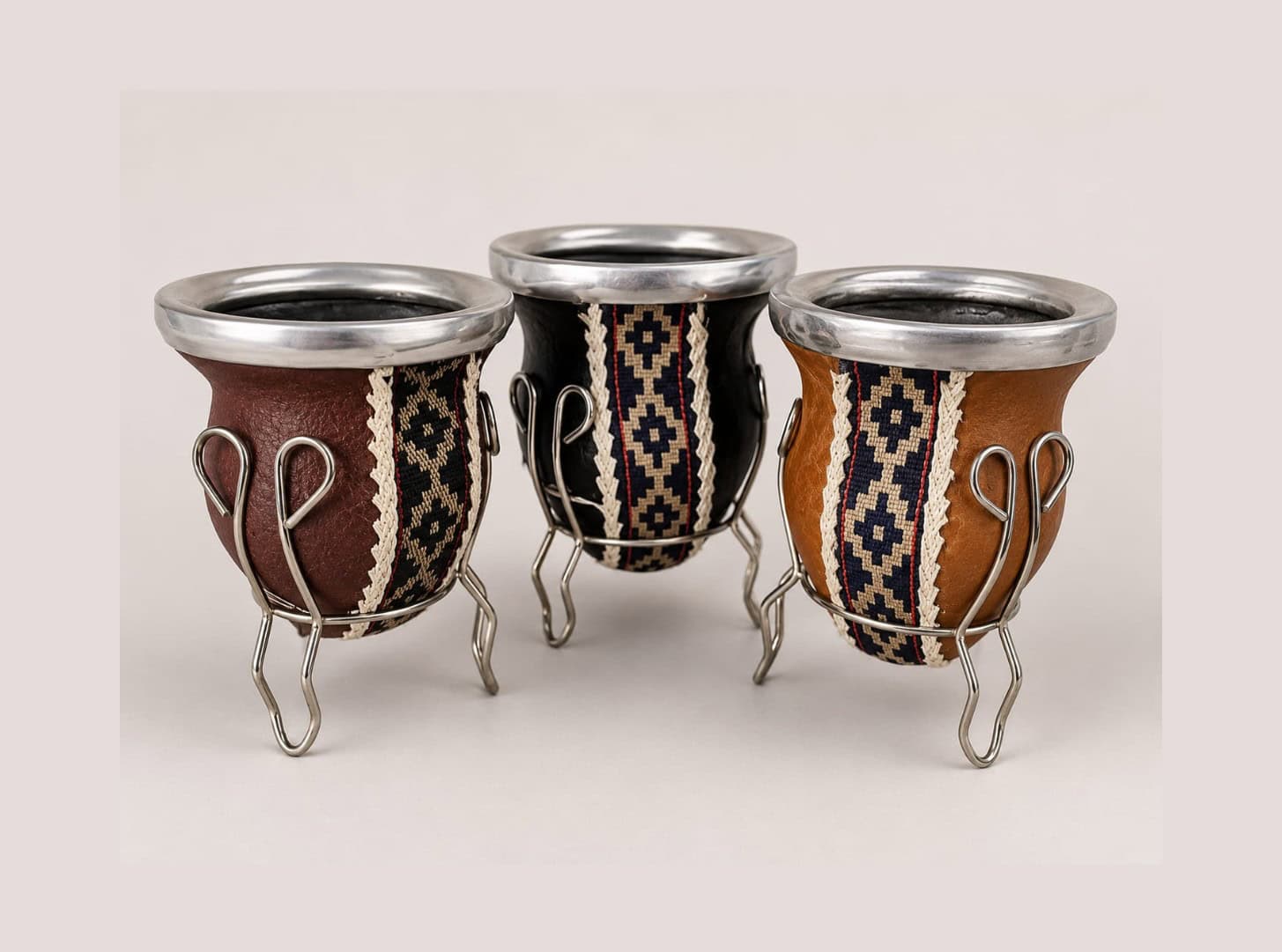 Traditional Argentine mate gourds with matching stands, handcrafted in genuine leather with alpaca silver rims and classic Guarda Pampa ribbon.