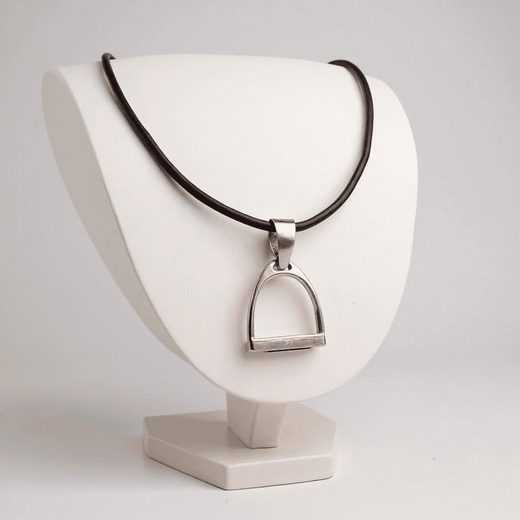 Oversized Iron Riding Stirrup pendant made of sterling silver on a dark leather choker, displayed on a white necklace stand