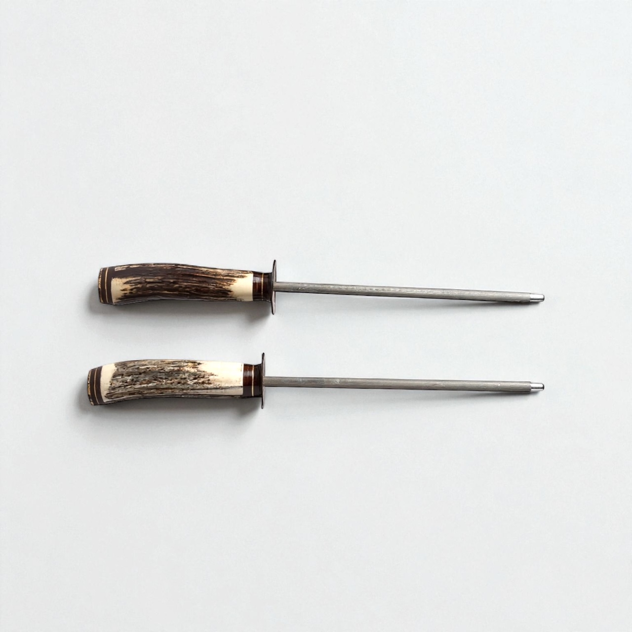 This handcrafted staghorn sharpening steel (chaira) combines functionality, tradition, and artistry in one remarkable piece. Each handle is made from genuine staghorn, polished to highlight its natural texture and unique grain. The result is a one-of-a-kind tool that feels solid, balanced, and comfortable in your hand. The 20 cm sharpening rod is forged from high-quality steel, providing the perfect length for sharpening long blades — from facones and hunting knives to fine chef’s knives. Its length ensures a smooth, controlled motion that helps maintain the blade’s original edge with precision. Each chaira is individually crafted in Argentina by artisans who preserve the gaucho legacy of knife-making. The elegant combination of staghorn, steel, and finely detailed brass rings makes this piece as beautiful as it is functional. Whether displayed alongside a traditional knife collection or used daily in the kitchen, this staghorn chaira brings authenticity, performance, and a touch of Argentine soul to every sharpening ritual. Material: Natural staghorn and forged steel Rod length: 20 cm Handcrafted in Argentina Ideal for: facones, collector knives, chef’s knives A timeless companion for those who appreciate craftsmanship and tradition.