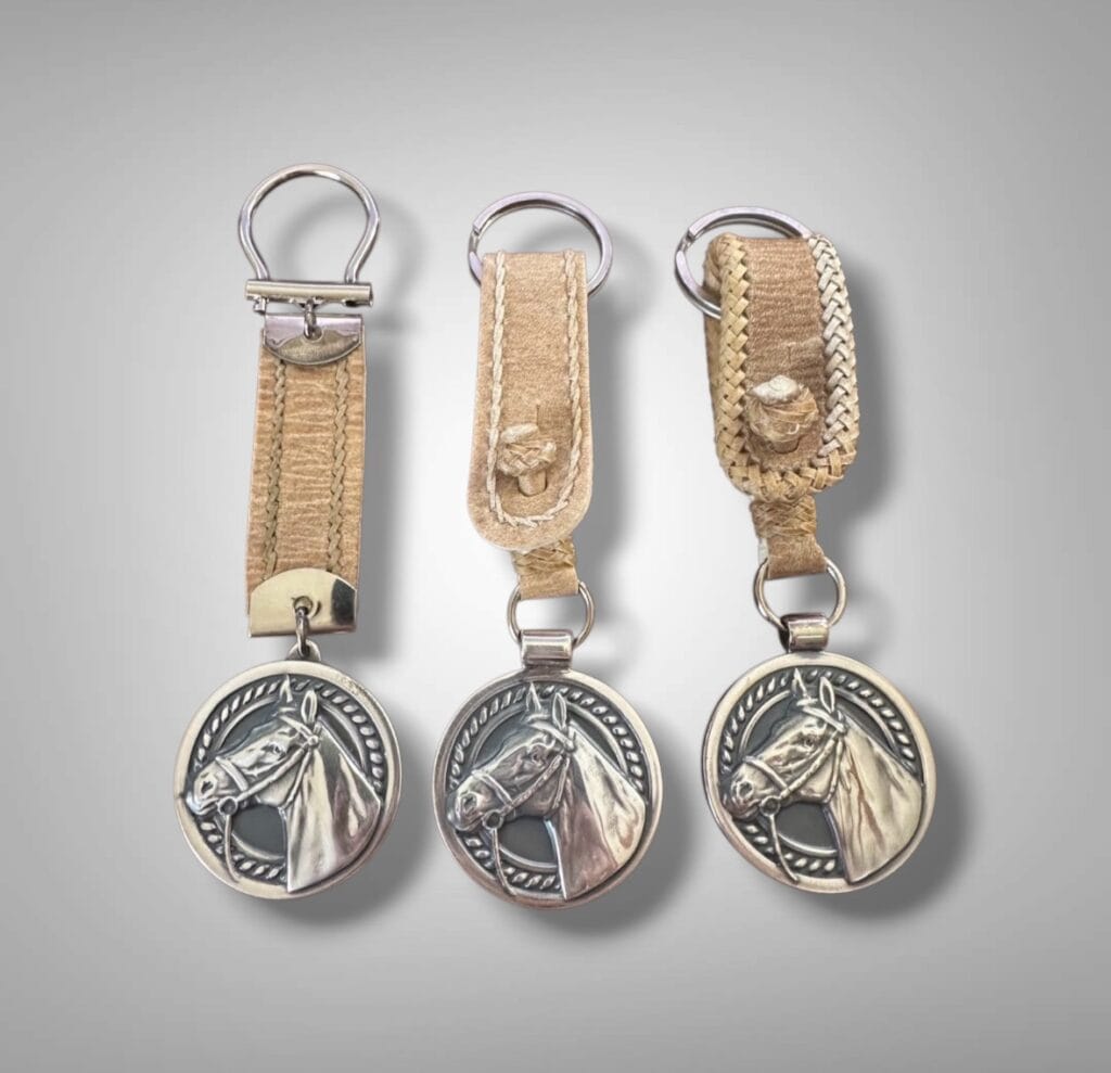 Handmade horse head keychains crafted in Argentina featuring silver-plated alpaca medallions and rawhide leather loops