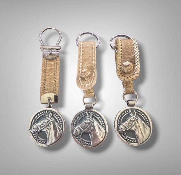 Handmade horse head keychains crafted in Argentina featuring silver-plated alpaca medallions and rawhide leather loops