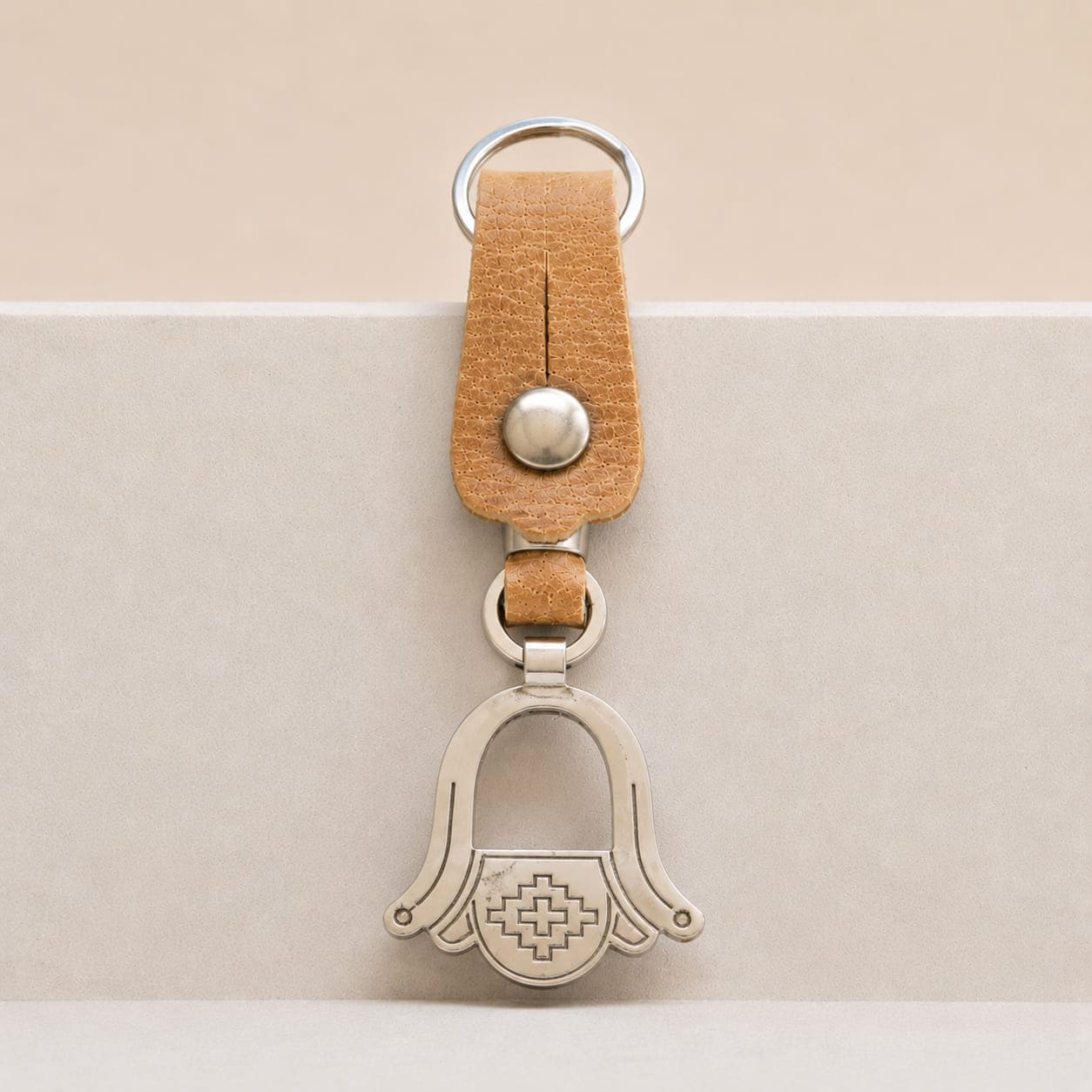 Handcrafted Argentine key ring featuring a natural leather loop and an openwork Alpaca silver medallion shaped as a traditional Criollo stirrup.