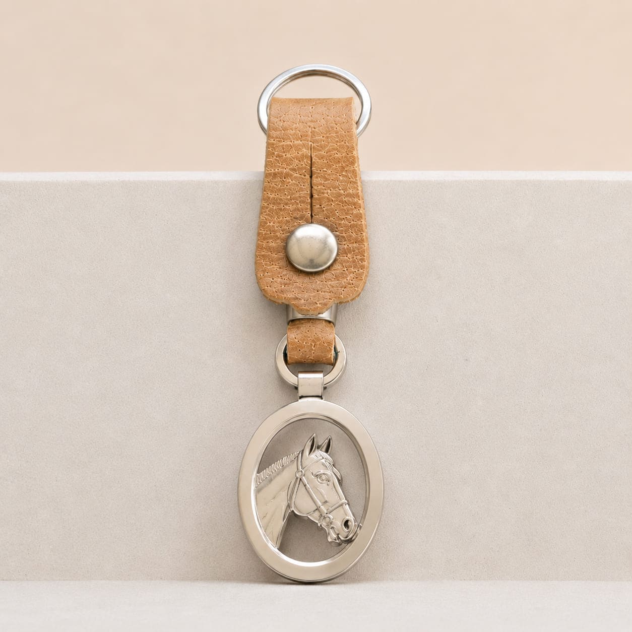 Handcrafted Argentine key ring with a natural leather loop and an openwork oval Alpaca silver medallion featuring a detailed horse head profile.