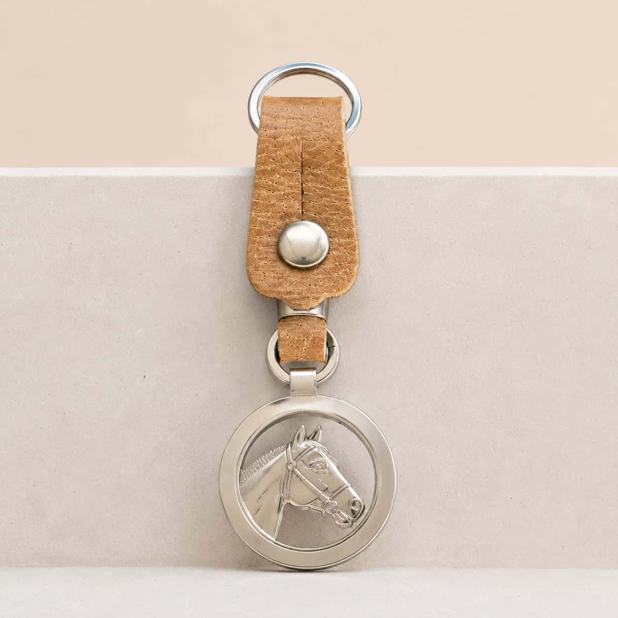 Handcrafted Argentine key ring featuring a natural leather loop and an openwork round Alpaca silver medallion with a detailed horse head profile.