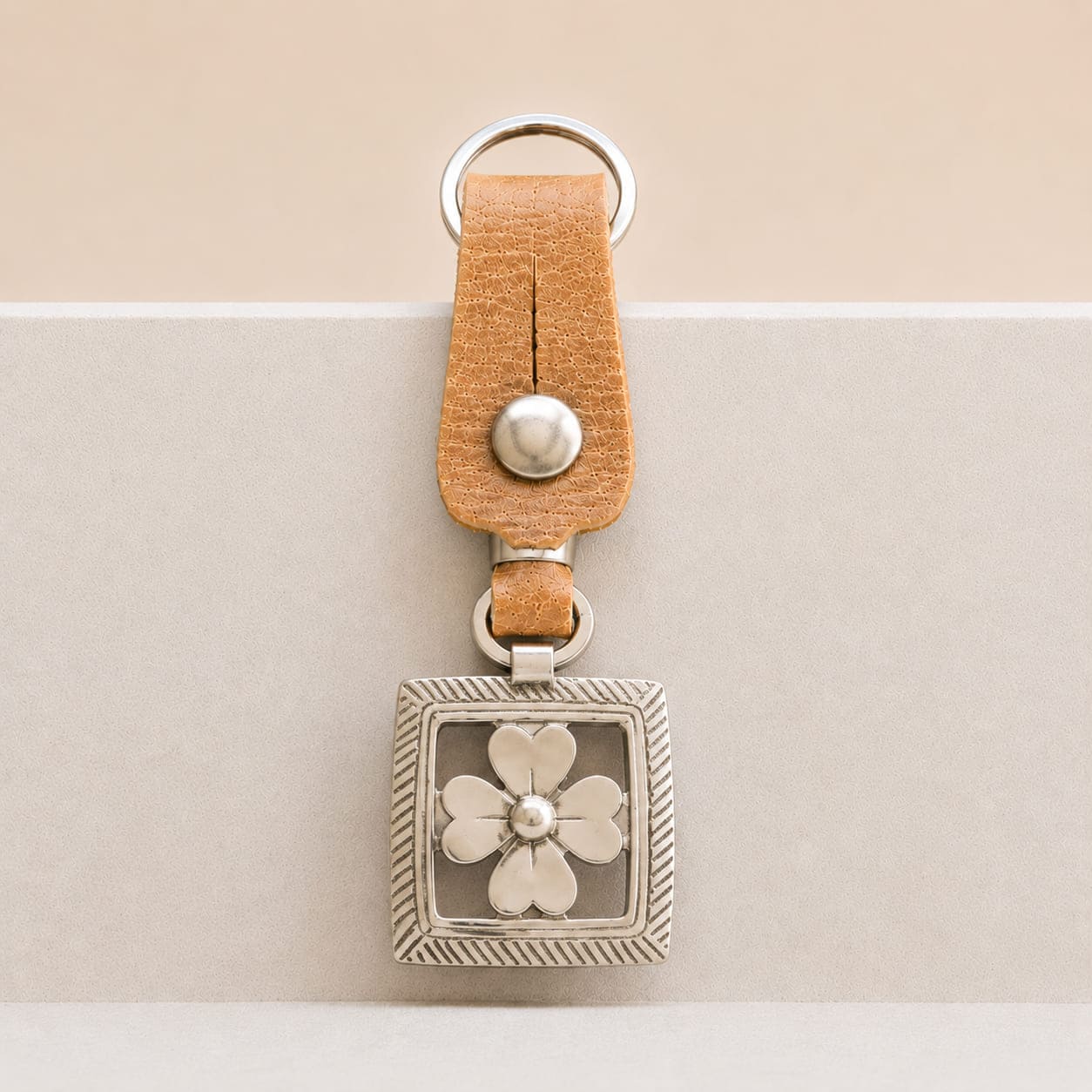 Handcrafted Argentine key ring featuring a natural leather loop and a round Alpaca silver medallion with an openwork four-petal blossom.