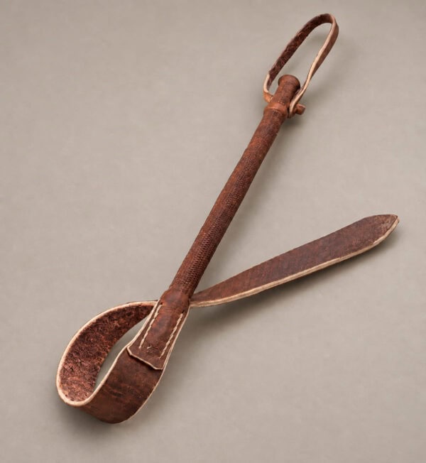 Brown Argentine leather rebenque laid flat with its strap extended and rustic brown interior visible.