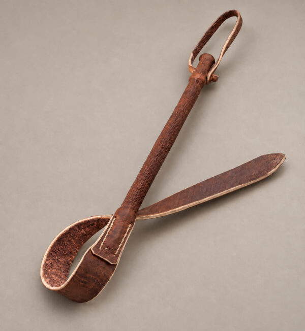 Brown Argentine leather rebenque laid flat with its strap extended and rustic brown interior visible.