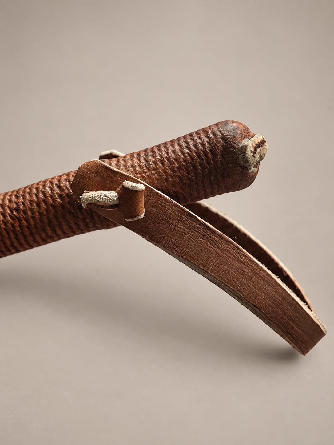 Close-up of an Argentine leather rebenque showing the textured handle and leather wrist loop attachment.